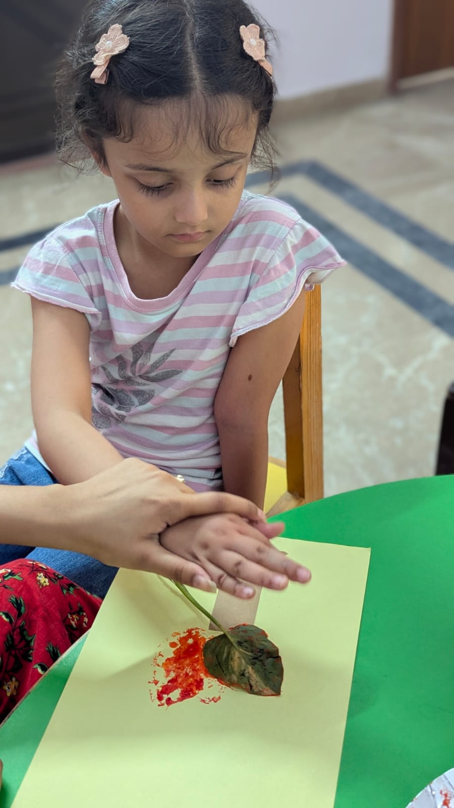Child guided through a leaf-printing art activity