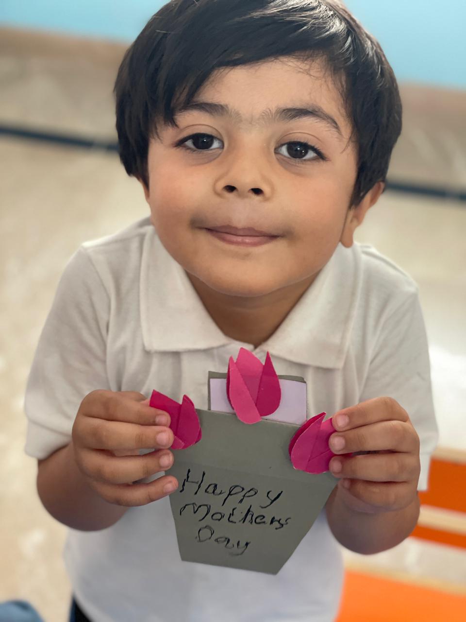Student proudly showing a handmade Mother's Day craft